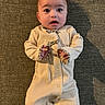 Lillian is registered to the contest to win money with this photo: baby, infant, onesie, clothing, carpet, floor, shadow, expression, wide_eyes, face, person, child, cute, indoor, texture, hands, portrait, laying_down, human, young
