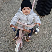 Mia a rejoint le concours — aidez-le/la à gagner de superbes lots ! toddler, child, tricycle, hat, pom_pom, jacket, gloves, mittens, outdoor, path, footwear, skirt, person, happy, smiling, toy, winter_clothing, baby_shoes, play, transportation