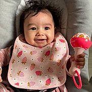 Inaya participe au concours pour gagner de l'argent avec cette photo : baby, infant, smiling, pink_bib, strawberry_pattern, rattle, cushioned_seat, happy, child, cute, portrait, baby_clothes, toy, indoor, young_child, person, seat_belt, head, hand, expressive_face