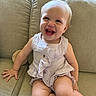 baby, button, child, clothing, couch, cute, face, furniture, hair, hand, happy, indoors, infant, leg, light, portrait, ruffles, sitting, skin, smiling