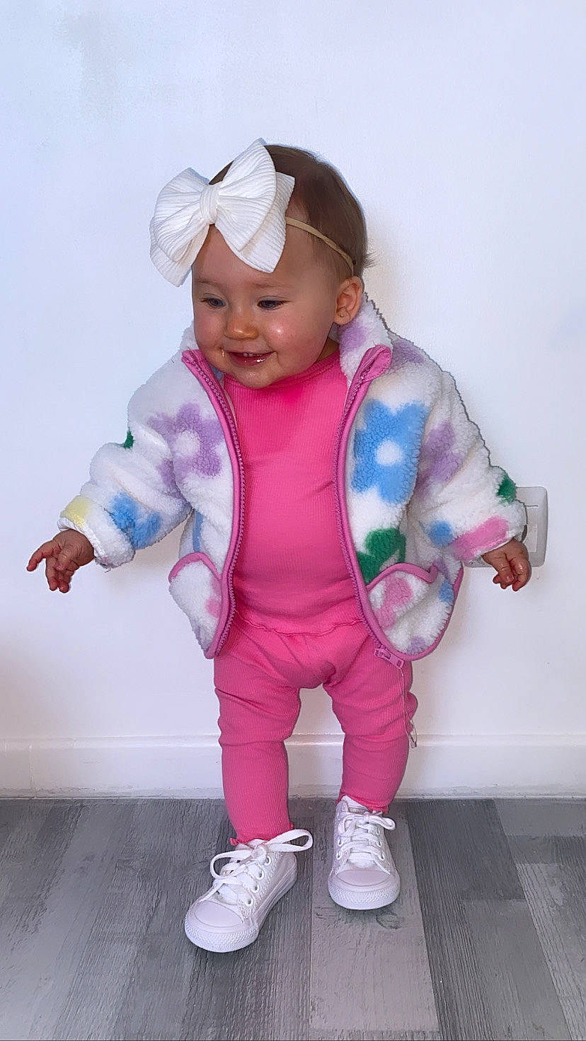 Mya participe au concours pour gagner de l'argent avec cette photo : baby, baby_toddler_clothing, child, electric_blue, face, fashion_accessory, finger, gesture, happy, headgear, headwear, human_body, joy, magenta, pattern, person, personal_protective_equipment, pink, purple, sleeve