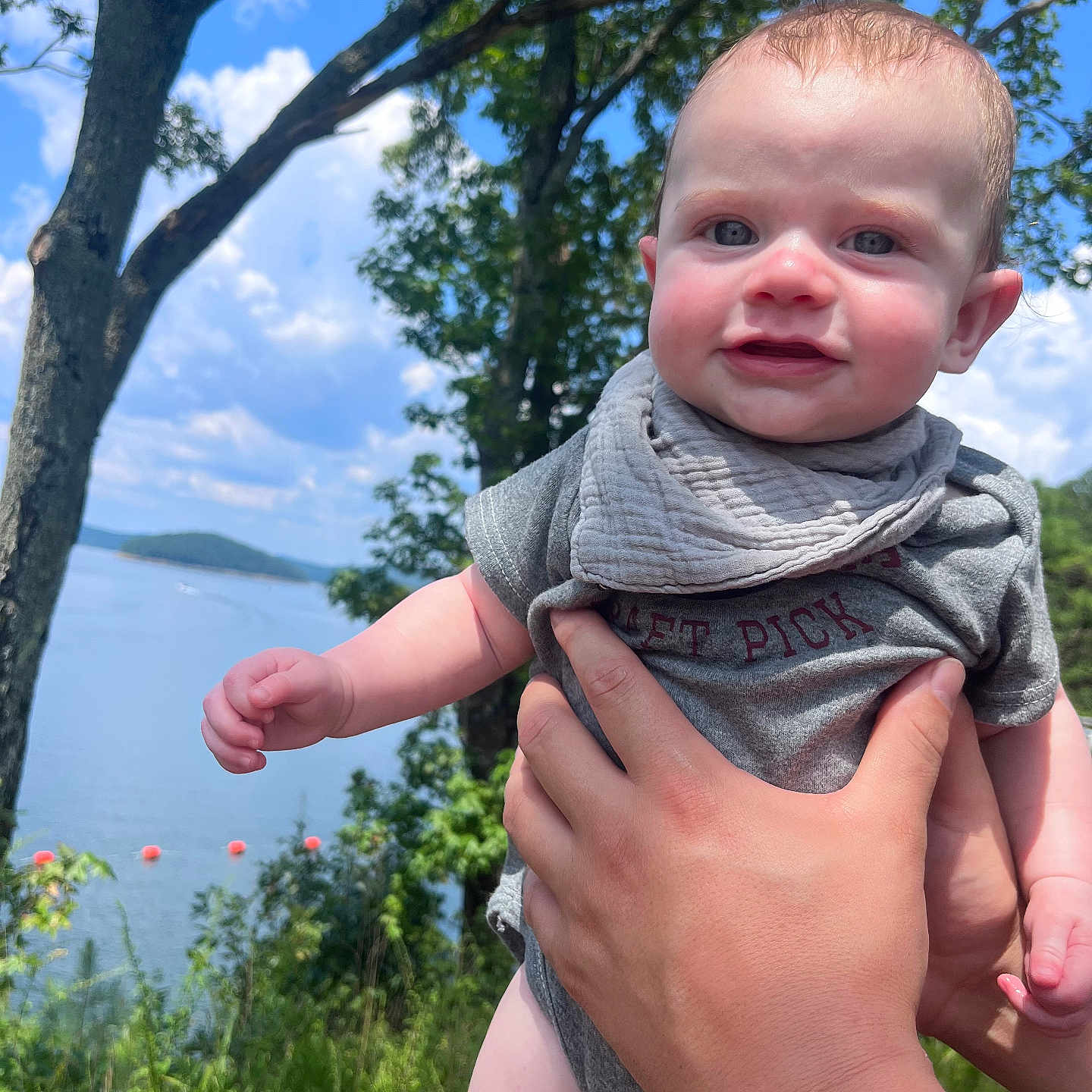 Lincoln is registered to the contest to win money with this photo: baby, bodypart, clothing, face, finger, grass, hand, head, lake, nature, outdoors, person, photography, plant, portrait, scarf, summer, tree, vegetation, water