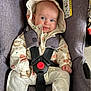 baby, child, car_seat, jacket, hood, straps, red_buckle, white_pants, cute, infant, seatbelt, safety, smiling, face, hands, indoor, clothing, person, seat, toddler