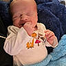 newborn, baby, infant, sleeping, yawning, smiling, face, portrait, blanket, blue_blanket, swaddled, onesie, clothing, hand, finger, indoor, cozy, close_up, seated, soft_lighting