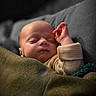 August joined the competition — help win amazing prizes! newborn, baby, infant, sleeping, face, portrait, hand, raised_hand, blanket, cozy, bed, clothing, long_sleeves, warm_lighting, indoors, closeup, peaceful, resting, soft_texture, family_photo