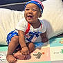 baby, child, smiling, sitting, play_mat, colorful, patriotic_clothing, stars, stripes, headwear, happy, indoors, foot, hand, person, infant, cushion, clothing, cute, portrait
