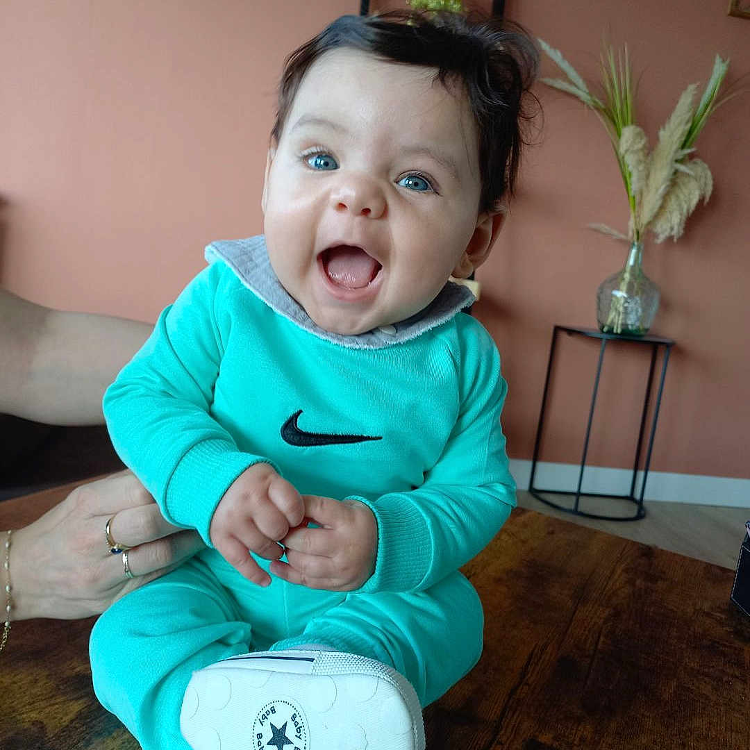 Ilyes participe au concours pour gagner de l'argent avec cette photo : baby, clothing, coat, face, footwear, happy, head, jacket, jar, pants, person, photography, plant, planter, portrait, pottedplant, pottery, shoe, sitting, vase