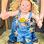 Ripp is registered to the contest to win money with this photo: adult, autumn_leaves, baby, blue_jeans, child, costume, cute, denim_overalls, floor, footwear, fun, holding_hands, indoor, person, playful, scarecrow_costume, smiling, straw, tile_floor, tongue_out