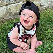 Oakland joined the competition — help win amazing prizes! baby, child, grass, outdoor, smiling, cap, jersey, sitting, happy, face, person, nature, foot, hand, stone_wall, wood, greenery, cute, summer, playful