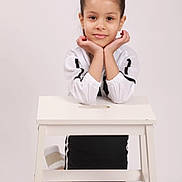 Jasmine is registered to the contest to win money with this photo: black_skirt, child, cute, face, fashion, footwear, girl, hair, hands, happy, kneeling, pink_bow, portrait, pose, smile, stool, studio, white_background, white_shirt, young