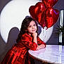 balloons, celebration, child, cute, decor, girl, heart_balloons, indoor, lighting, long_hair, marble_table, party, portrait, red_dress, shadow, smile, spotlight, table, thinking, young