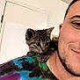 Fluke Ellington is registered to the contest to win money with this photo: kitten, cat, man, shoulder, tie_dye_shirt, indoor, portrait, cute, pet, young_cat, colorful_clothing, smile, human, animal, companion, curious, close_up, casual, friendship, domestic