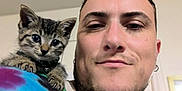 Fluke Ellington joined the competition — help win amazing prizes! man, cat, kitten, shoulder, selfie, indoor, tie_dye_shirt, tabby, young_adult, facial_hair, earring, smile, pet, animal, cute, curious, portrait, casual, friendship, home