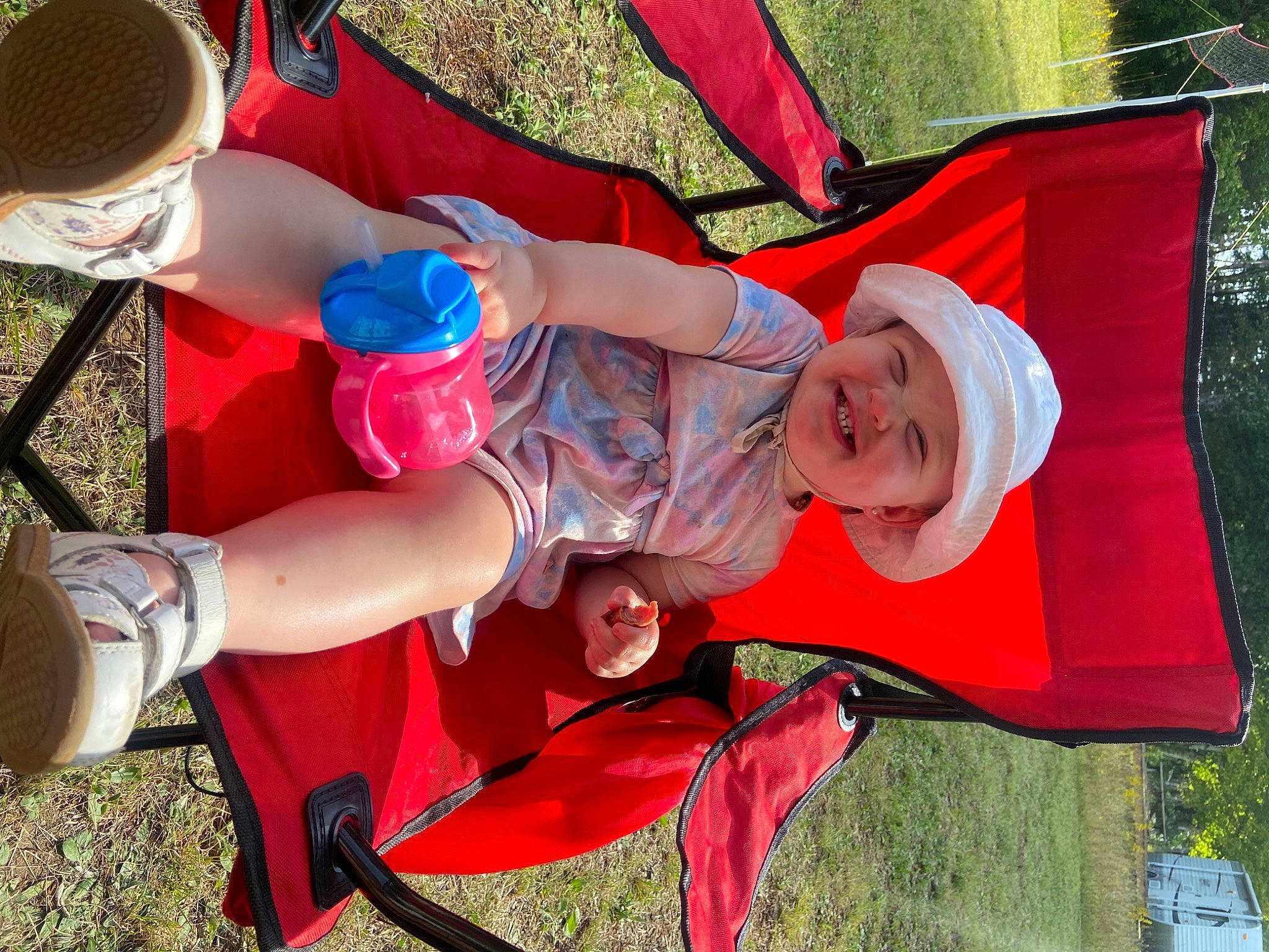 Nova is registered to the contest to win money with this photo: chair, child, event, fun, grass, happy, hat, headwear, joy, lap, leisure, orange, person, plant, recreation, shoe, shorts, smile, sneakers, sun_hat