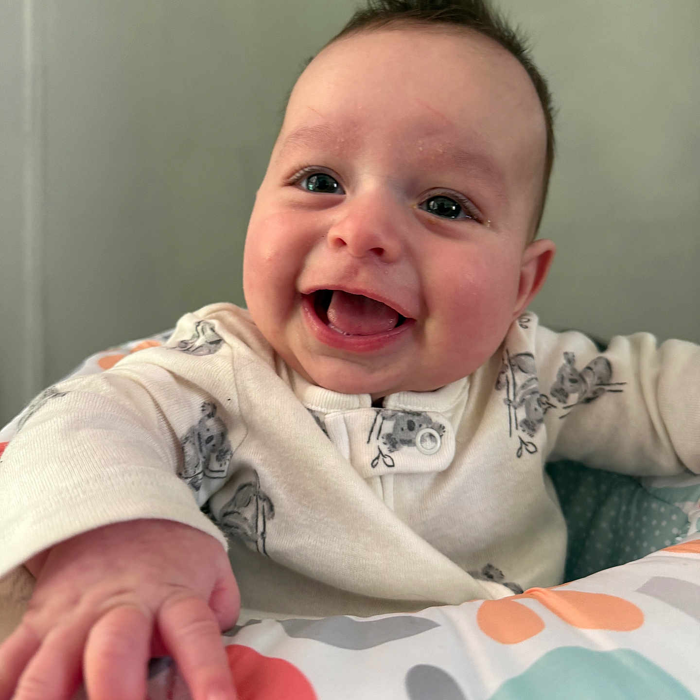 Noah joined the competition — help win amazing prizes! baby, child, smiling, happy, hand, face, onesie, indoor, play_area, colorful, infant, cute, expression, portrait, person, young_child, cozy, reaching, mohawk, closeup