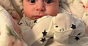 Noah is registered to the contest to win money with this photo: baby, infant, blanket, floral, onesie, stars, face, eyes, expression, cute, indoors, soft, warm, cozy, child, newborn, person, portrait, sleepwear, comfort
