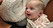 Elizabeth is registered to the contest to win money with this photo: adult, baby, black_clothing, blanket, closeup, comfort, cozy, cuddle, expression, face, happy, head, indoor, infant, person, portrait, skin, smiling, soft_texture, warmth