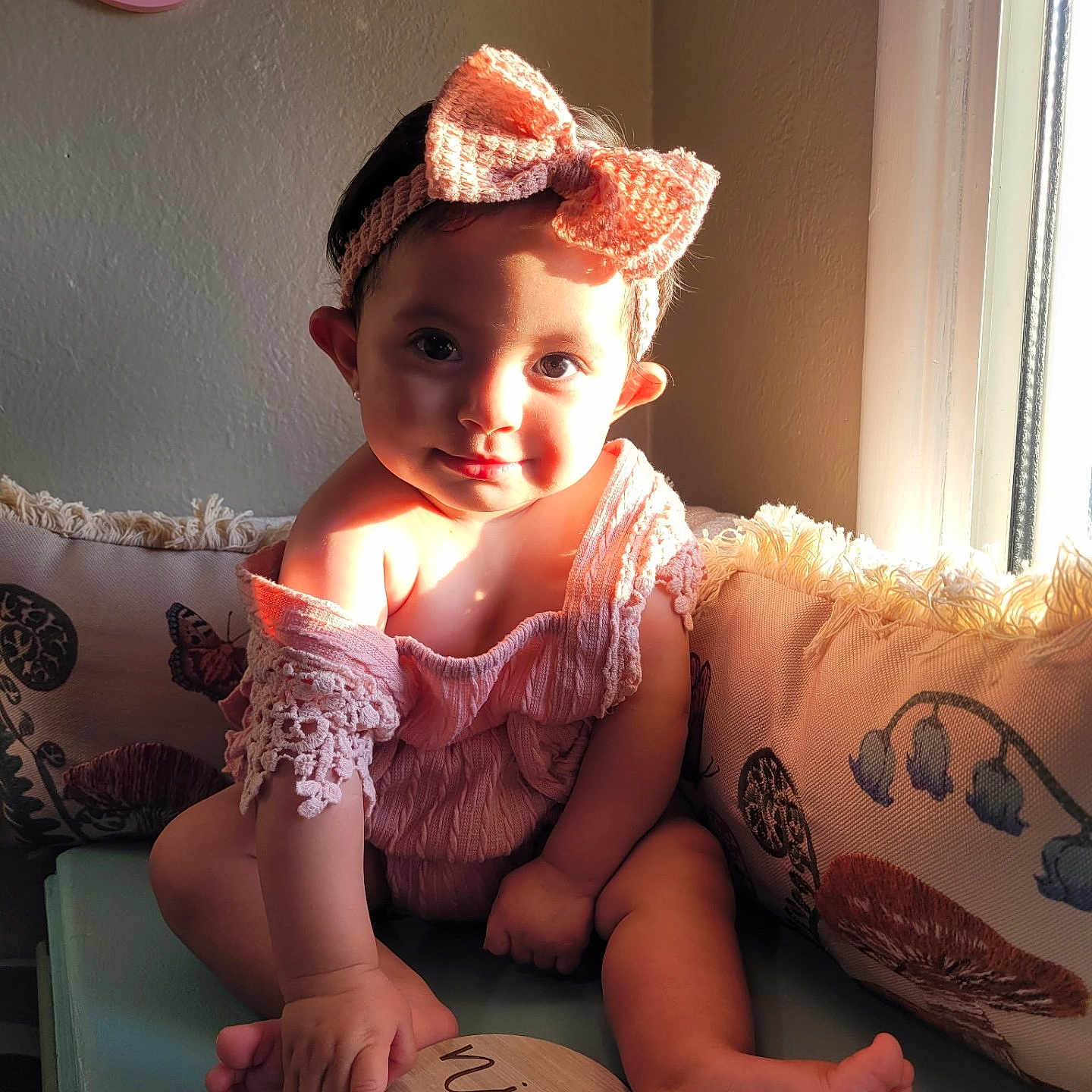 Frannie joined the competition — help win amazing prizes! baby, bench, bow, child, cushion, cute, flower_wall_decor, foot, girl, hand, headband, indoor, nine_months, pink_outfit, portrait, sitting, smiling, sunlight, window, wooden_sign