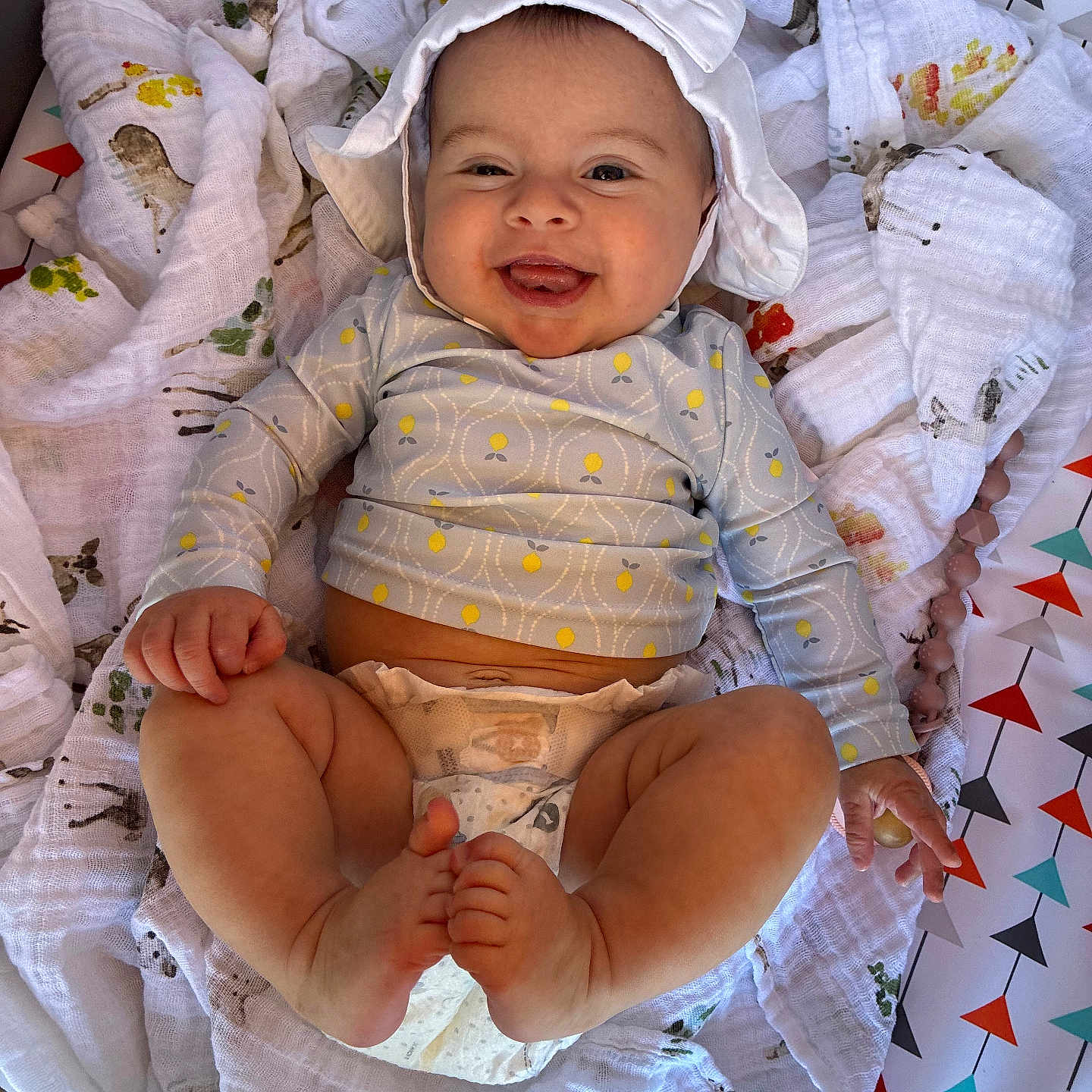 Briley joined the competition — help win amazing prizes! baby, smiling, infant, hat, bow, blanket, diaper, clothing, happy, cute, chubby_legs, toes, lying_down, patterned_blanket, colorful, indoors, playful, portrait, child, young