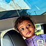 Nyra is registered to the contest to win money with this photo: child, car, car_seat, headrest, jacket, purple_clothing, face, curly_hair, window, rain, windshield, expression, portrait, indoors, seat, young_child, casual_clothing, looking_away, daylight, closeup