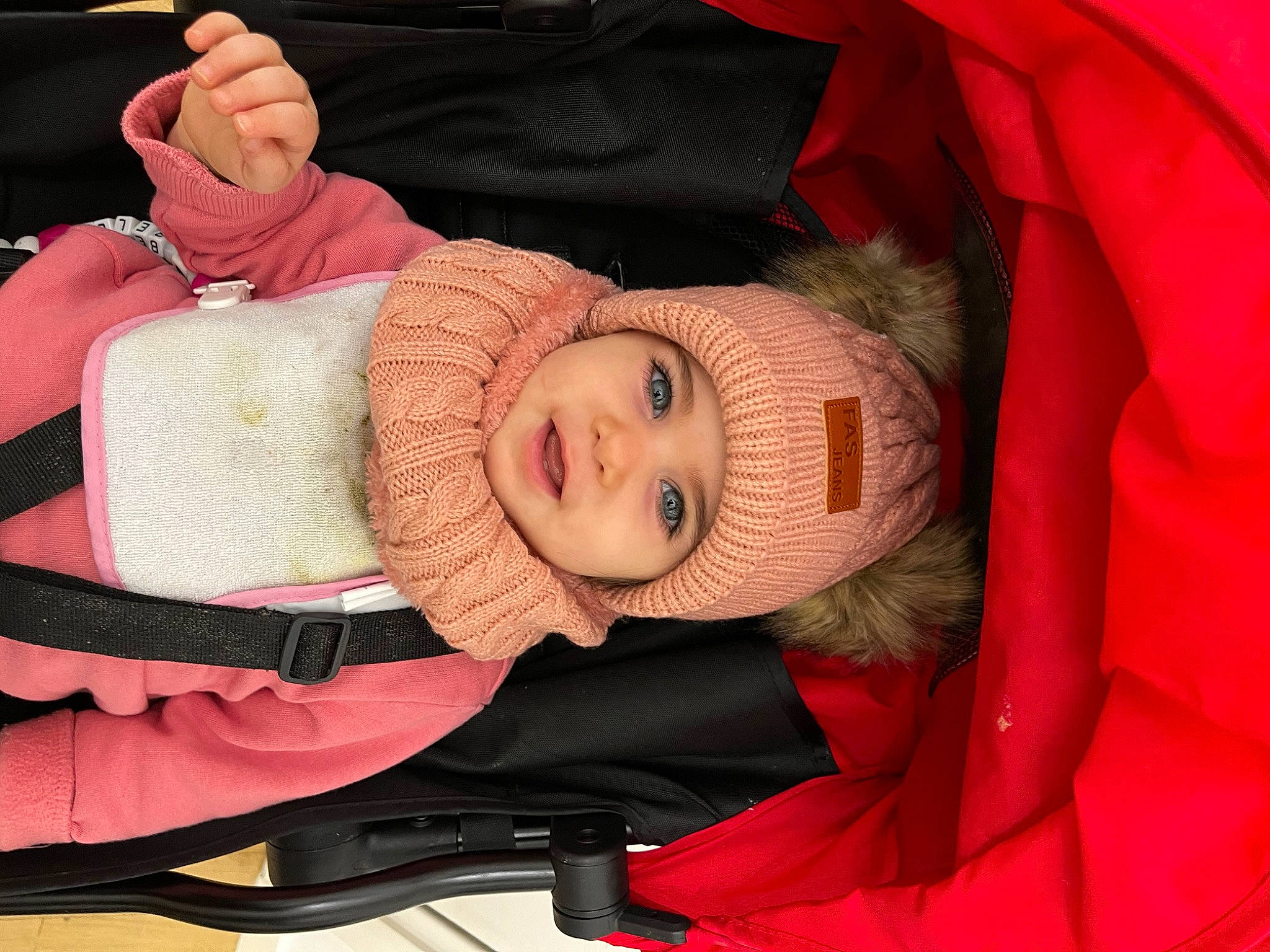 Bella participe au concours pour gagner de l'argent avec cette photo : arm, baby, baby_carriage, baby_products, cheek, child, comfort, finger, gesture, hand, head, headwear, lap, mouth, person, pink, sitting, skin, sleeve, smile