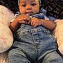 baby, denim_overalls, headband, blue_bow, infant, cushion, pillow, hand, face, eyes, clothing, cute, indoor, person, portrait, relaxing, baby_clothes, skin, small_hands, bed