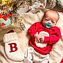 baby, infant, christmas_tree, christmas_lights, christmas_ornament, stocking, blanket, pajamas, pacifier, holiday, festive, snow_flocked_tree, red_clothing, cozy, indoors, cute, newborn, decorations, soft_texture, celebration