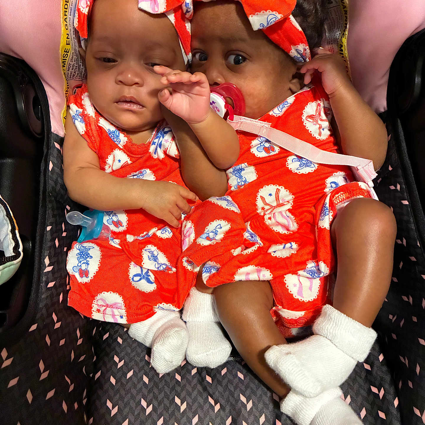Paris London is registered to the contest to win money with this photo: adorable, baby, child, close_up, clothing, cuddling, cute, cute_babies, headband, indoors, infant, matching_outfits, newborn, orange_outfit, pacifier, person, sleepy, stroller, twin_babies, white_socks