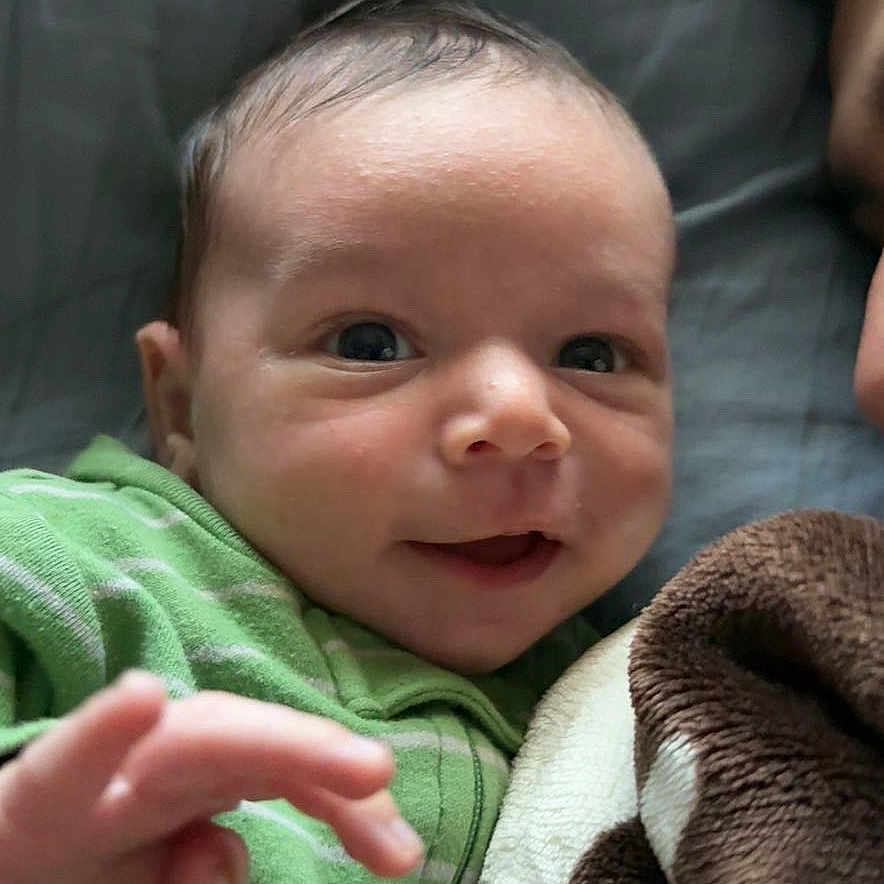 Michael is registered to the contest to win money with this photo: baby, blanket, bodypart, couch, cushion, face, finger, furniture, hand, happy, head, homedecor, laughing, newborn, person, photography, portrait, quilt, selfie, smile