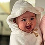 baby, infant, hood, towel, cozy, smiling, happy, chubby_cheeks, big_eyes, portrait, closeup, indoor, being_held, clothing, button, plush_texture, warm_lighting, adorable, expression, soft_skin