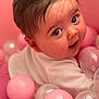 baby, infant, face, eyes, smile, pink, ball_pit, toy_balls, hair, cheeks, portrait, closeup, adorable, playful, white_shirt, indoor, soft_texture, glossy_balls, looking_up, child