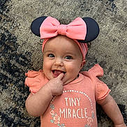 Melinda joined the competition — help win amazing prizes! baby, infant, smiling, pink_clothing, headband, bow, finger_in_mouth, carpet, cute, child, happy, toddler, portrait, indoor, playful, person, apparel, fashion, face, expression