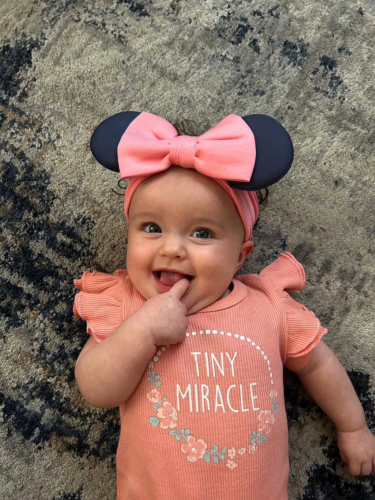 Melinda joined the competition — help win amazing prizes! baby, infant, smiling, pink_clothing, headband, bow, finger_in_mouth, carpet, cute, child, happy, toddler, portrait, indoor, playful, person, apparel, fashion, face, expression
