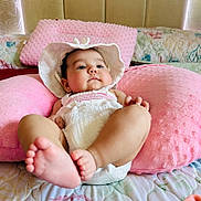 Nicol Aylen joined the competition — help win amazing prizes! baby, infant, pink_pillow, hat, white_clothing, bed, blanket, foot, face, skin, child, cute, resting, indoor, soft_texture, plush, cozy, headwear, person, sleepwear