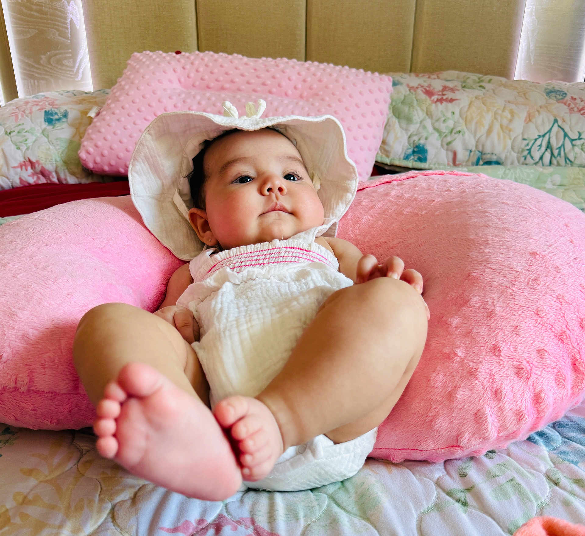 Nicol Aylen joined the competition — help win amazing prizes! baby, infant, pink_pillow, hat, white_clothing, bed, blanket, foot, face, skin, child, cute, resting, indoor, soft_texture, plush, cozy, headwear, person, sleepwear