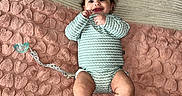 Elianys is registered to the contest to win money with this photo: baby, infant, smiling, lying_down, blanket, heart_pattern, pacifier, onesie, couch, pillow, gratitude, indoor, happy, child, person, soft_texture, cozy, cute, home, relaxed