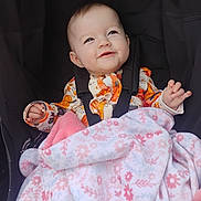 Ivy joined the competition — help win amazing prizes! baby, smiling, blanket, floral_pattern, stroller, child, clothing, happy, infant, seated, cute, portrait, toddler, warm, comfort, baby_girl, face, expression, indoors, soft