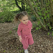 Asiyah a rejoint le concours — aidez-le/la à gagner de superbes lots ! child, toddler, pink_jumpsuit, outdoor, garden, trees, greenery, wood_chips, nature, curious, walking, daylight, plants, young_child, casual_clothing, playful, hair_tied, leaves, bushes, exploring