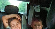 Peyton is registered to the contest to win money with this photo: blanket, car_seat, casual, child, family, greenery, happy, indoor, interior, kid, people, portrait, seat, serious, smiling, transportation, travel, vehicle, window, young