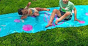 Peyton joined the competition — help win amazing prizes! child, children, playing, slip_and_slide, water, grass, outdoor, summer, fun, laughing, splash, greenery, backyard, fence, casual_clothing, barefoot, sunlight, recycling_bins, happy, active