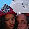 child, adult, firefighter_helmet, face, people, vehicle, white_car, outdoor, evening, portrait, funny_face, kiss_face, selfie, curly_hair, casual_clothing, headwear, closeup, together, expression, text_overlay