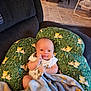 Zachariah is registered to the contest to win money with this photo: baby, blanket, cushion, green, fox_pattern, chair, tile_floor, wooden_chair, infant, smiling, indoors, cozy, cute, person, seated, comfort, home, child, soft, fabric