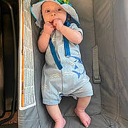 Elijah is registered to the contest to win money with this photo: baby, infant, hat, romper, shark_design, baby_seat, gray, hands, feet, cute, curious, indoor, child, clothing, comfort, nibbling, soft_lighting, playful, young, person