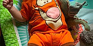 Elijah joined the competition — help win amazing prizes! baby, infant, onesie, orange_clothing, plush_toy, play_mat, tigger, laying_down, child, cute, soft_light, indoor, colorful, expression, person, legs, arms, face, toy, floor_mat