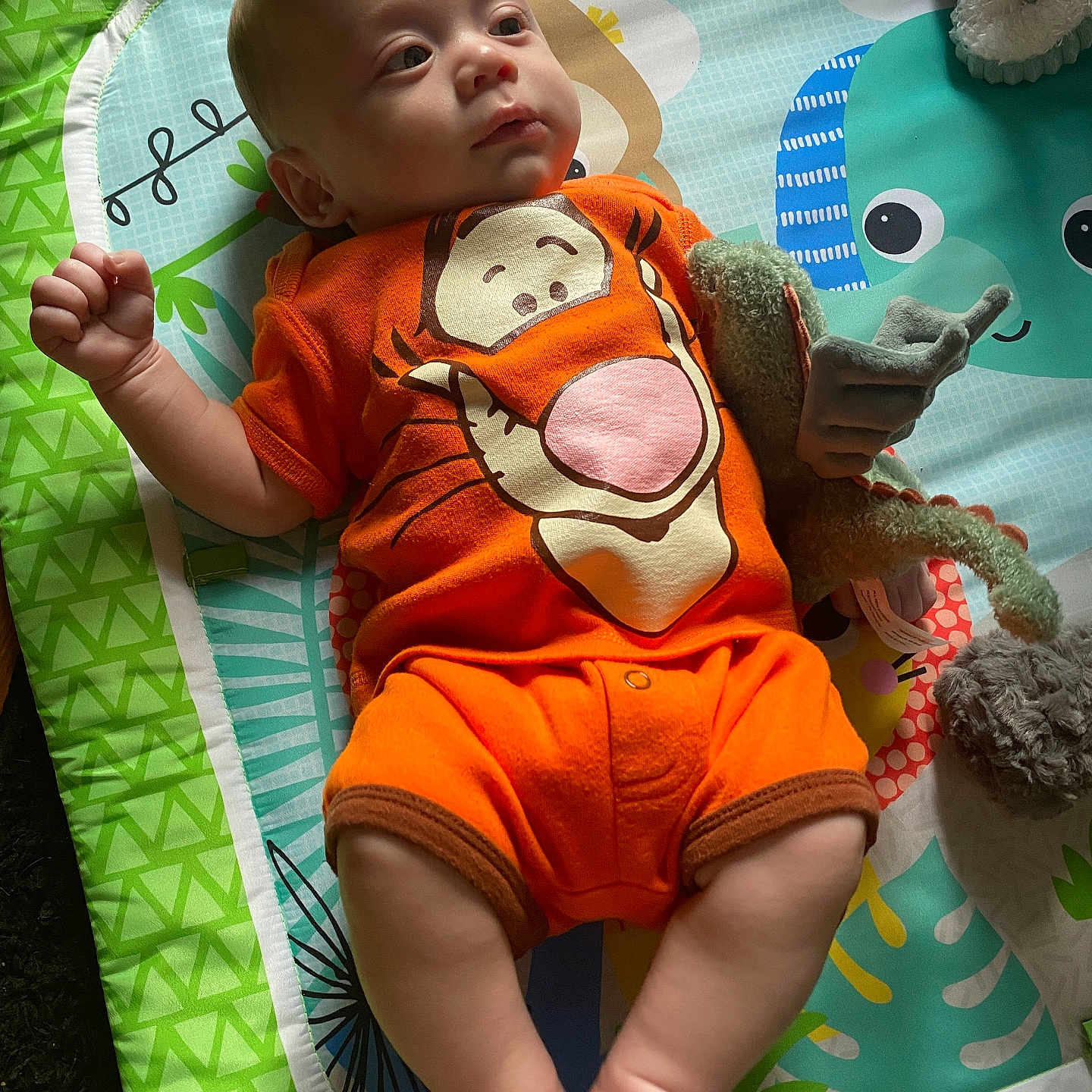 Elijah joined the competition — help win amazing prizes! arms, baby, child, colorful, cute, expression, face, floor_mat, indoor, infant, laying_down, legs, onesie, orange_clothing, person, play_mat, plush_toy, soft_light, tigger, toy