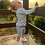 Emilio participe au concours pour gagner de l'argent avec cette photo : casual_clothing, child, cute, daylight, denim, greenery, hair_tied, nature, outdoor, pebble_floor, portrait, shoes, side_view, socks, standing, sunglasses, sunlight, sunset, toddler, wooden_railing
