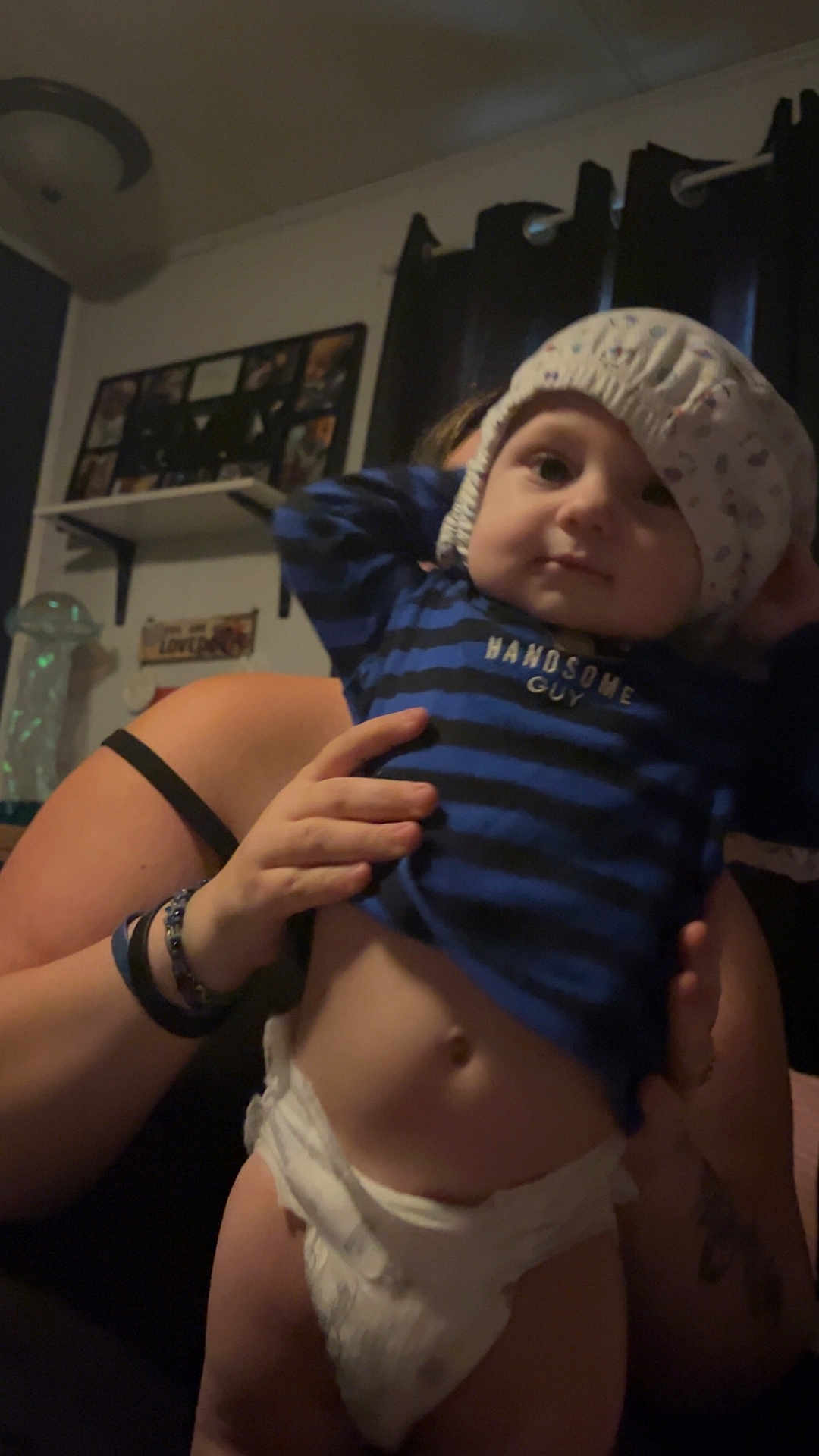Nashton joined the competition — help win amazing prizes! baby, diaper, child, person, indoor, shirt, striped_clothing, hand, holding, curtains, shelf, photoframe, adult, face, headwear, expression, room, dim_light, casual, home