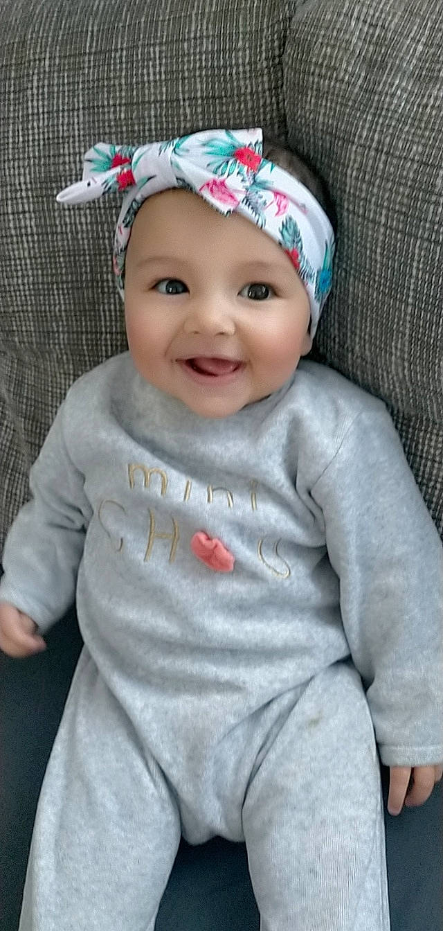 Julia a rejoint le concours — aidez-le/la à gagner de superbes lots ! baby, baby_toddler_clothing, cap, child, costume_hat, dress, eye, face, facial_expression, grey, happy, head, headwear, joy, lip, outerwear, person, pink, sleeve, smile