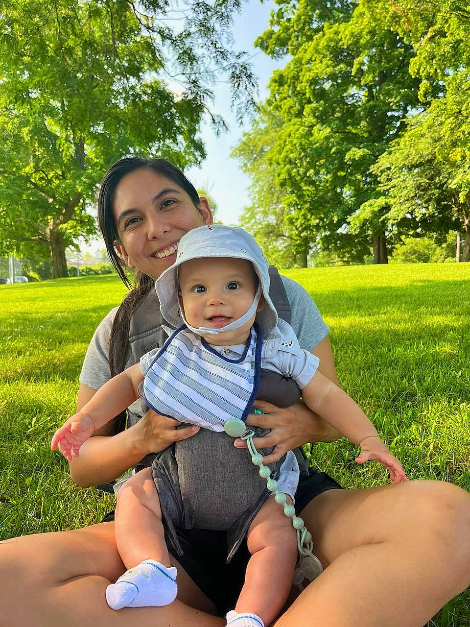 Aster is registered to the contest to win money with this photo: baby, baby_toddler_clothing, eye, fun, grass, green, happy, hat, headwear, joy, lap, leisure, morning, people, people_in_nature, person, plant, recreation, smile, sunlight