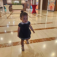 Inaya a rejoint le concours — aidez-le/la à gagner de superbes lots ! toddler, child, walking, marble_floor, lobby, indoor, dress, sandals, shadow, artwork, table, plant, ceiling_lights, person, hallway, wall_art, furniture, young_child, small_person, interior